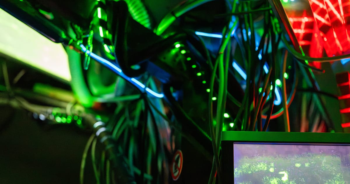 Tangled cables glowing in green, blue and red neon in a dark room